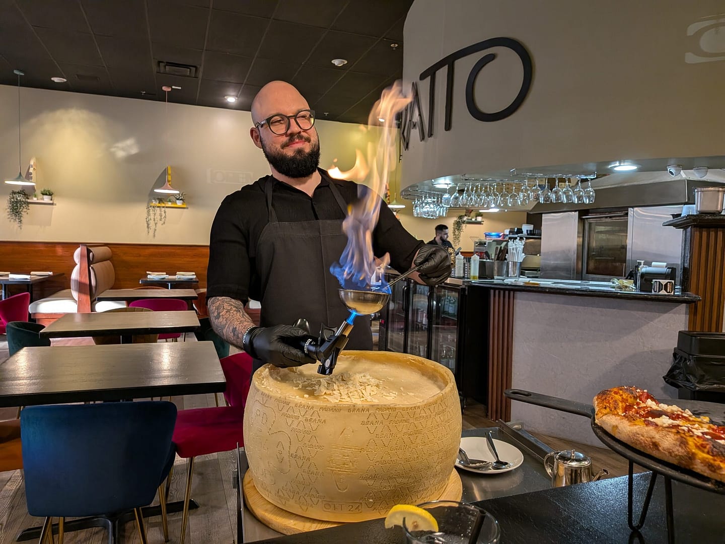 Chef flambeing a giant cheese wheel tableside at Tratto Avalon Park